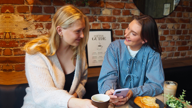 To kvinner på kafé handler fond i spraeroboten Nora